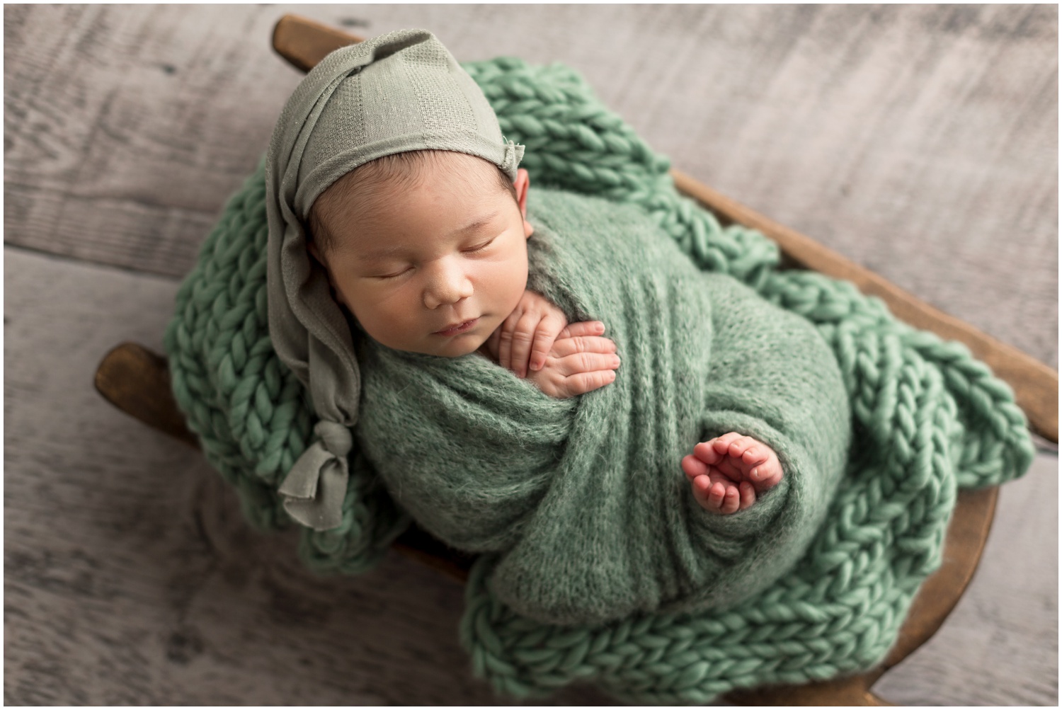 Dublin Ohio newborn baby boy photography session wrapped in hand knit sage green wrap in rustic wood propr